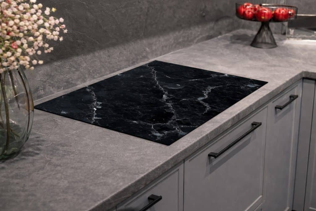 Inductiebeschermer met een luxe zwart marmeren print en witte aders.